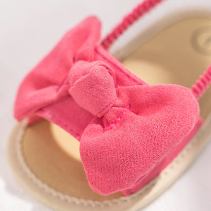 Close-up of the soft brushed fabric pink bow on a baby girl's soft sole sandal.