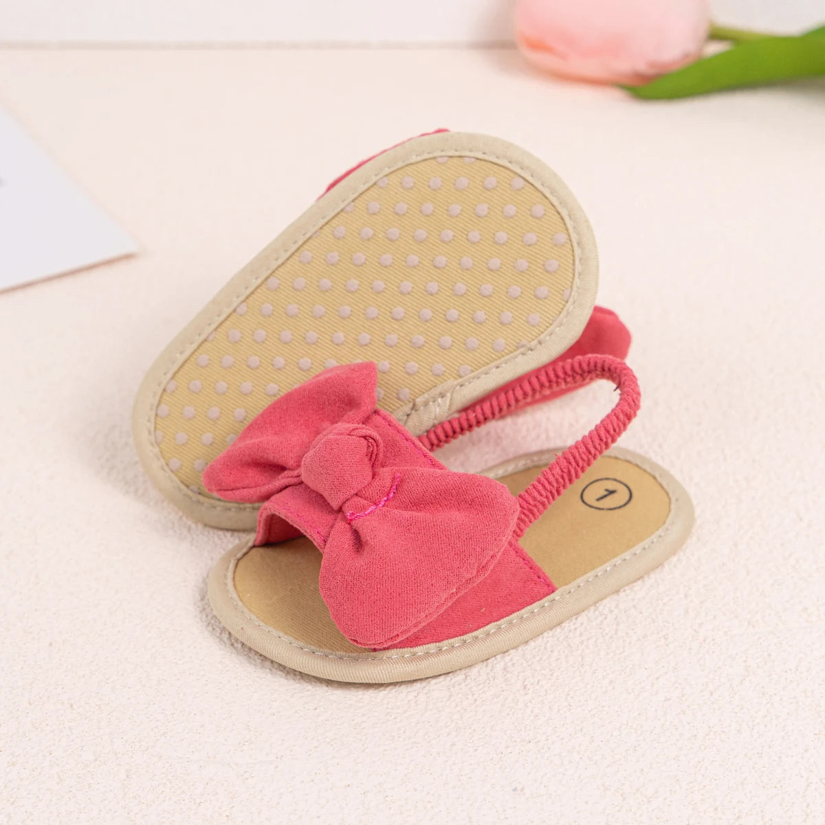 Bottom of a pink baby sandal showing the dotted anti-slip grip sole for early walkers.