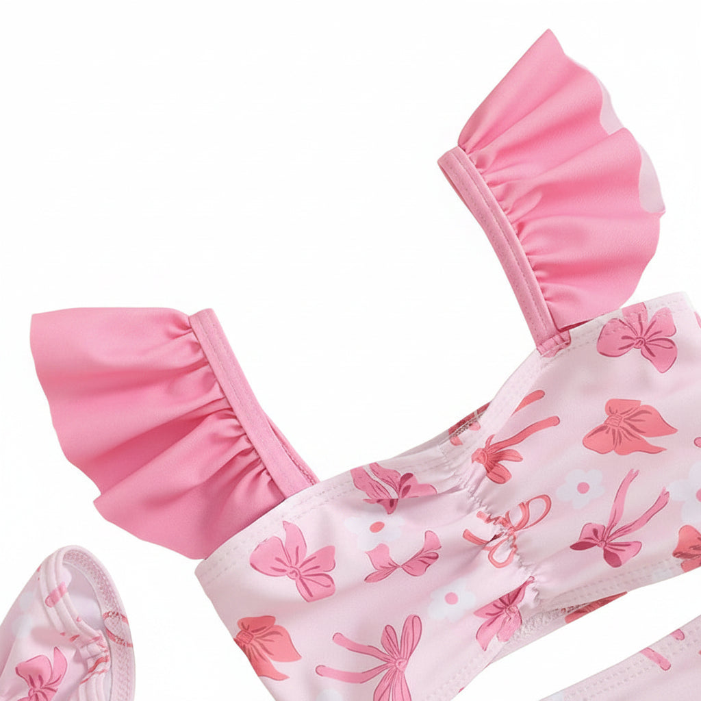 Close-up of high-stretch pink bow print fabric and ruffle sleeve detail on a toddler girl's bathing suit.