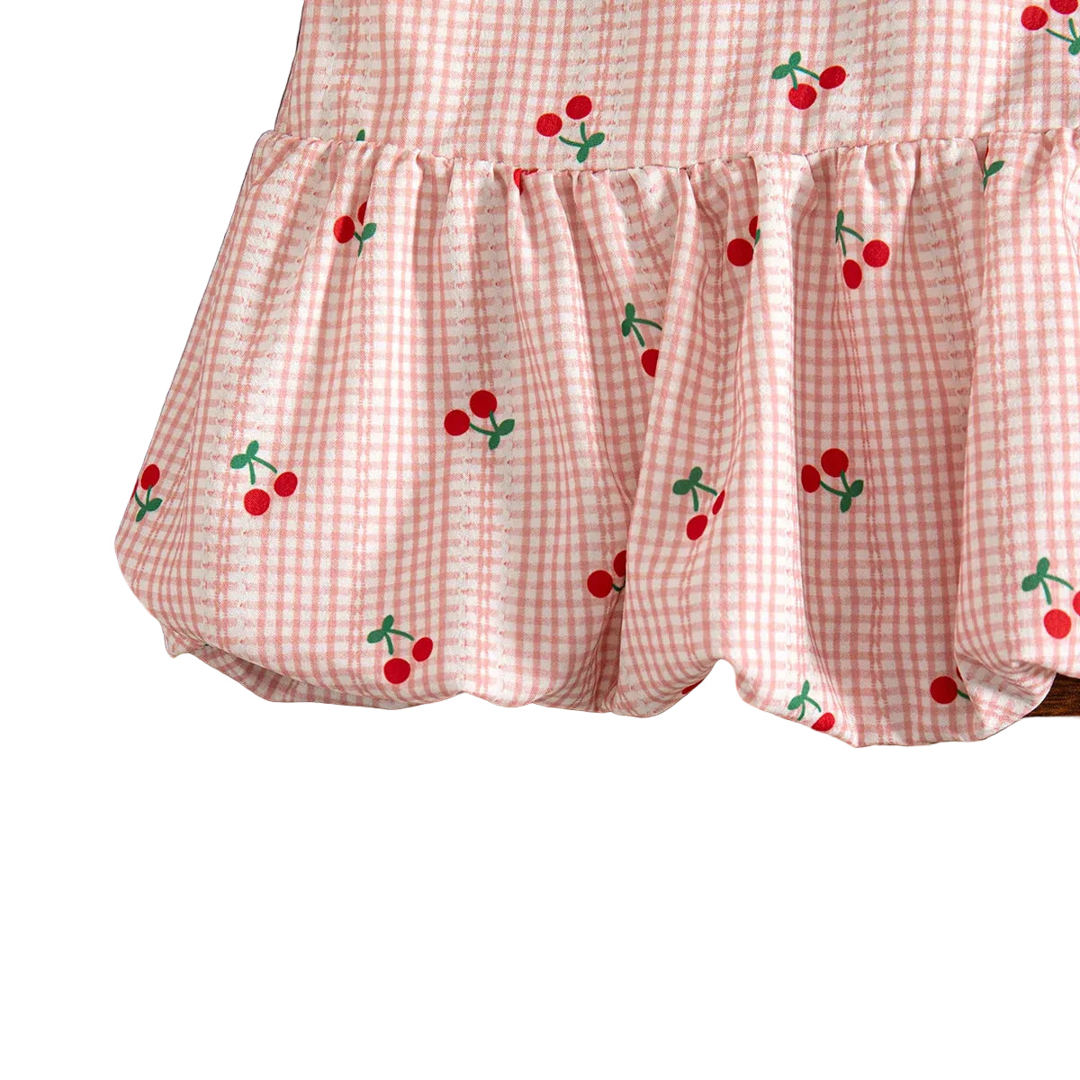 Close-up showing the gathered, voluminous bubble hemline and cherry print pattern on the pink gingham dress.