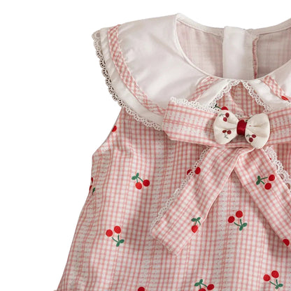 Close-up detail of the white ruffle Peter Pan collar and center bow with cherry appliqué on the pink gingham dress.