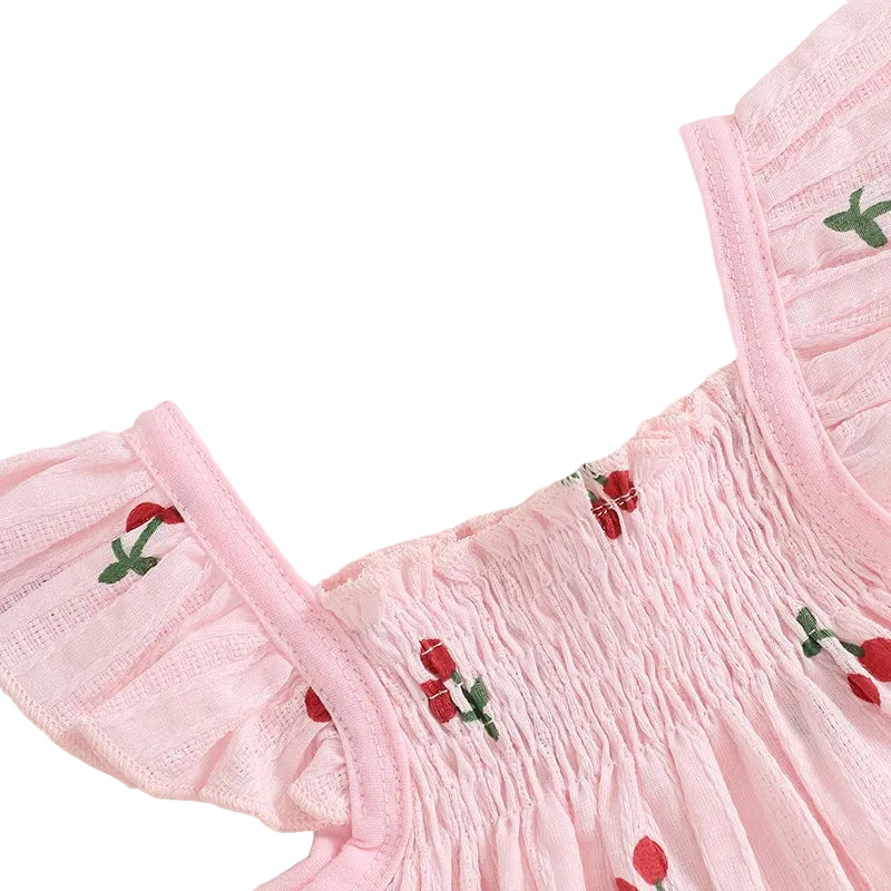 Detailed close-up of the blush pink smocked top, highlighting the elastic bodice and delicate fly sleeves with red cherry print.