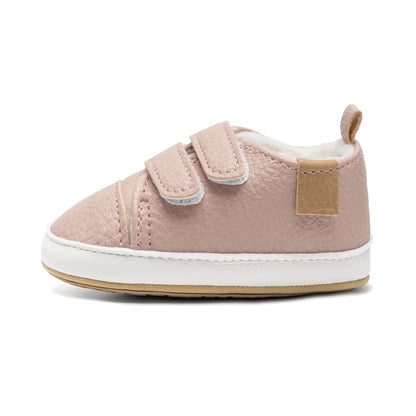 Side profile view of a single pink fleece-lined baby sneaker showing its soft, flexible construction and flat sole.