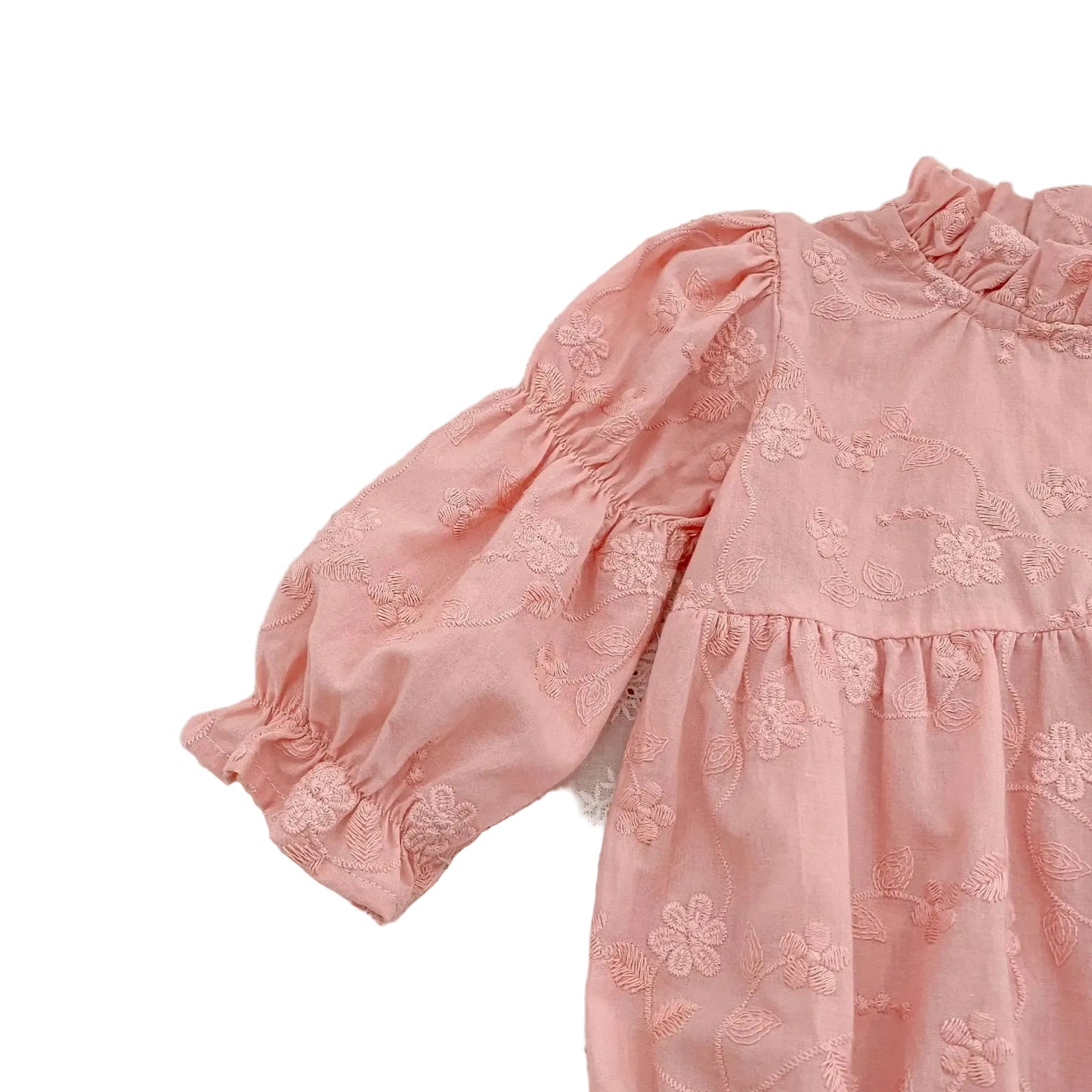 Close-up of the long bishop sleeve featuring a gathered shoulder on a pink floral embroidered baby romper.