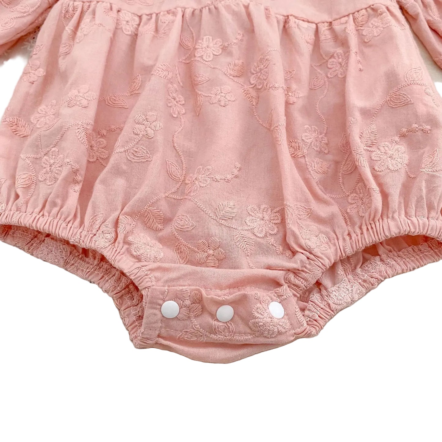 Close-up of the gathered leg openings and bubble silhouette of a pink floral embroidered baby romper.
