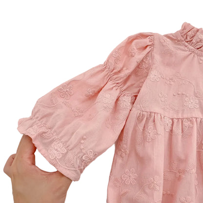 Close-up showing the elasticized ruffle cuff on the sleeve of a pink floral baby romper.