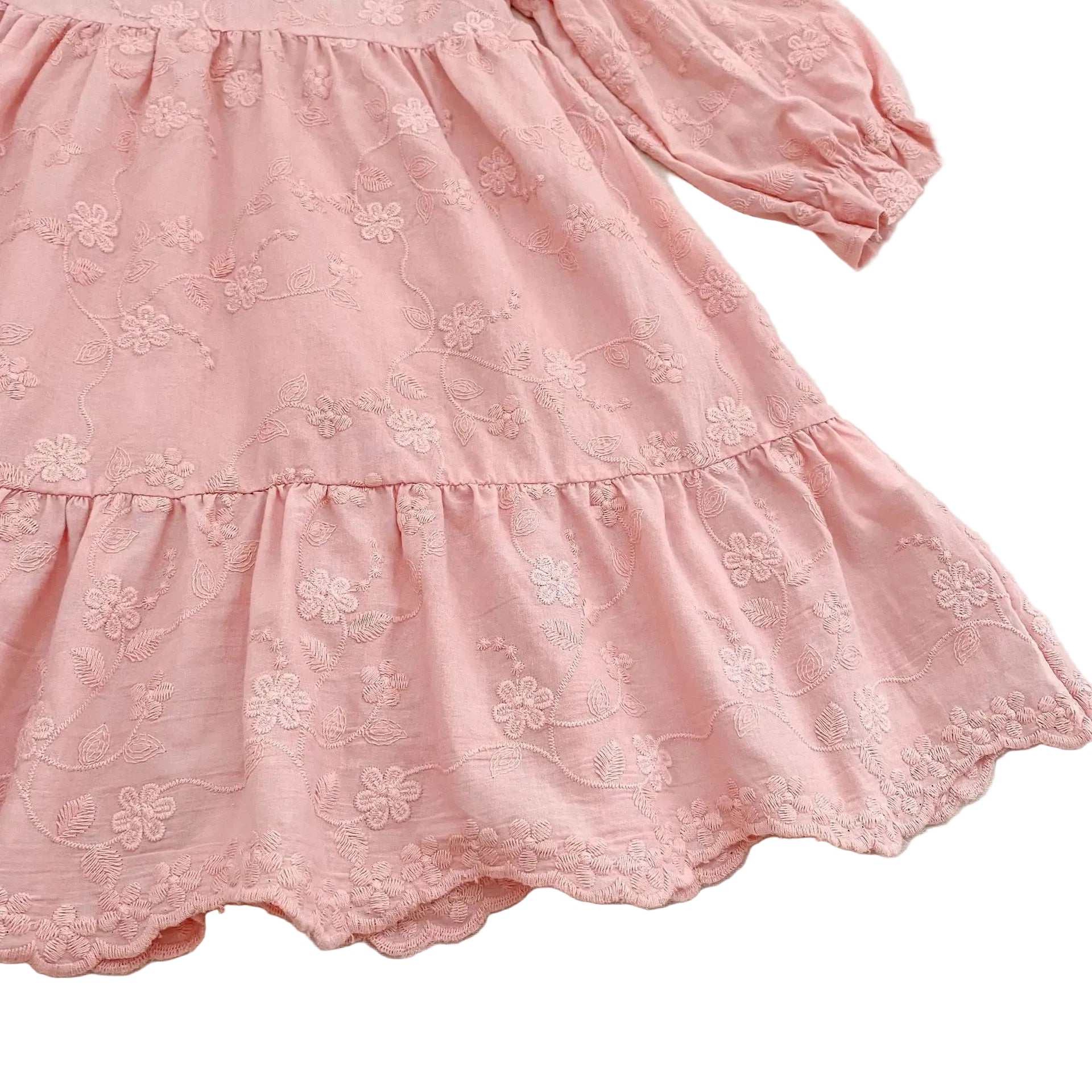 Close-up of the gathered flowing tiered skirt on a pink floral boutique dress for girls.