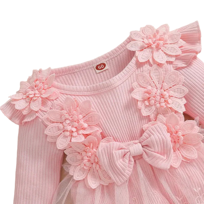 Close up of the pink baby girl romper dress showing the ribbed knit bodice, 3D floral appliques, and center bow.