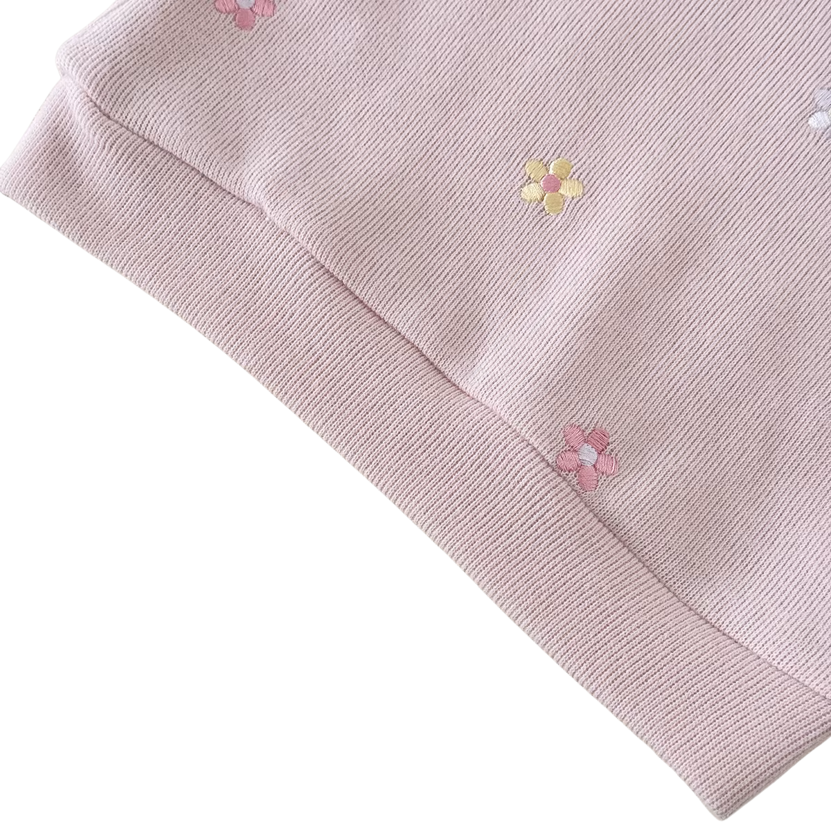 Close-up of the dusty pink sweatshirt's ribbed hem and soft combed cotton fabric with embroidered flowers.