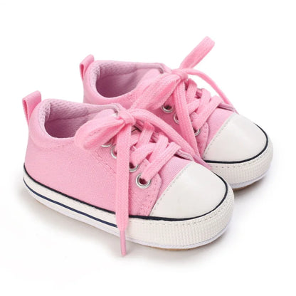 Soft pink infant athletic sneakers for baby girls, featuring a durable canvas upper.