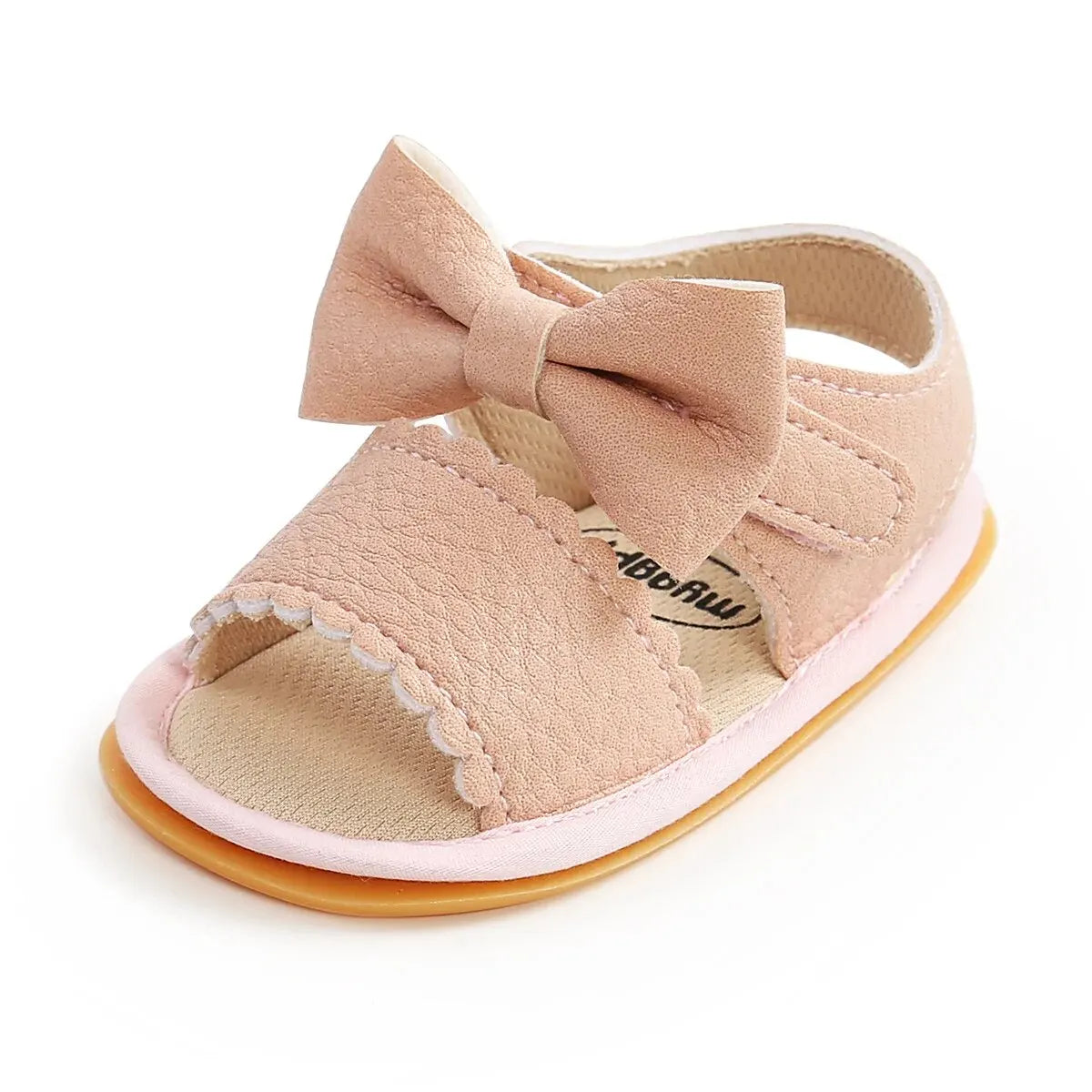 Studio front-facing shot of pink infant girl walking sandals highlighting the wide toe box, scalloped upper band, and matching leather bowknot.
