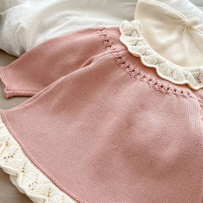 Back view close-up of a pink baby knit cardigan sweater showing the detailed white scalloped lace collar and hemline.