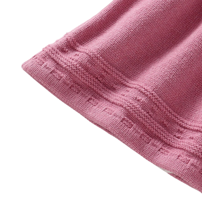 Close-up of the textured bottom hemline stitching on a pink knit dress for baby girls.