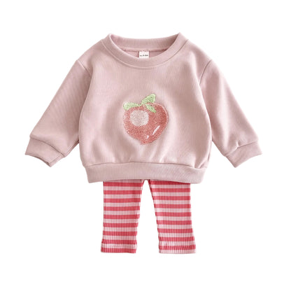 Flat lay of a baby and toddler girls two-piece outfit featuring a pink long-sleeve sweatshirt with a peach graphic and pink-and-white striped leggings on a white background.