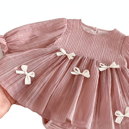 Close-up of the dusty pink baby dress showing the crinkled pleated nylon texture and delicate white bow appliques.