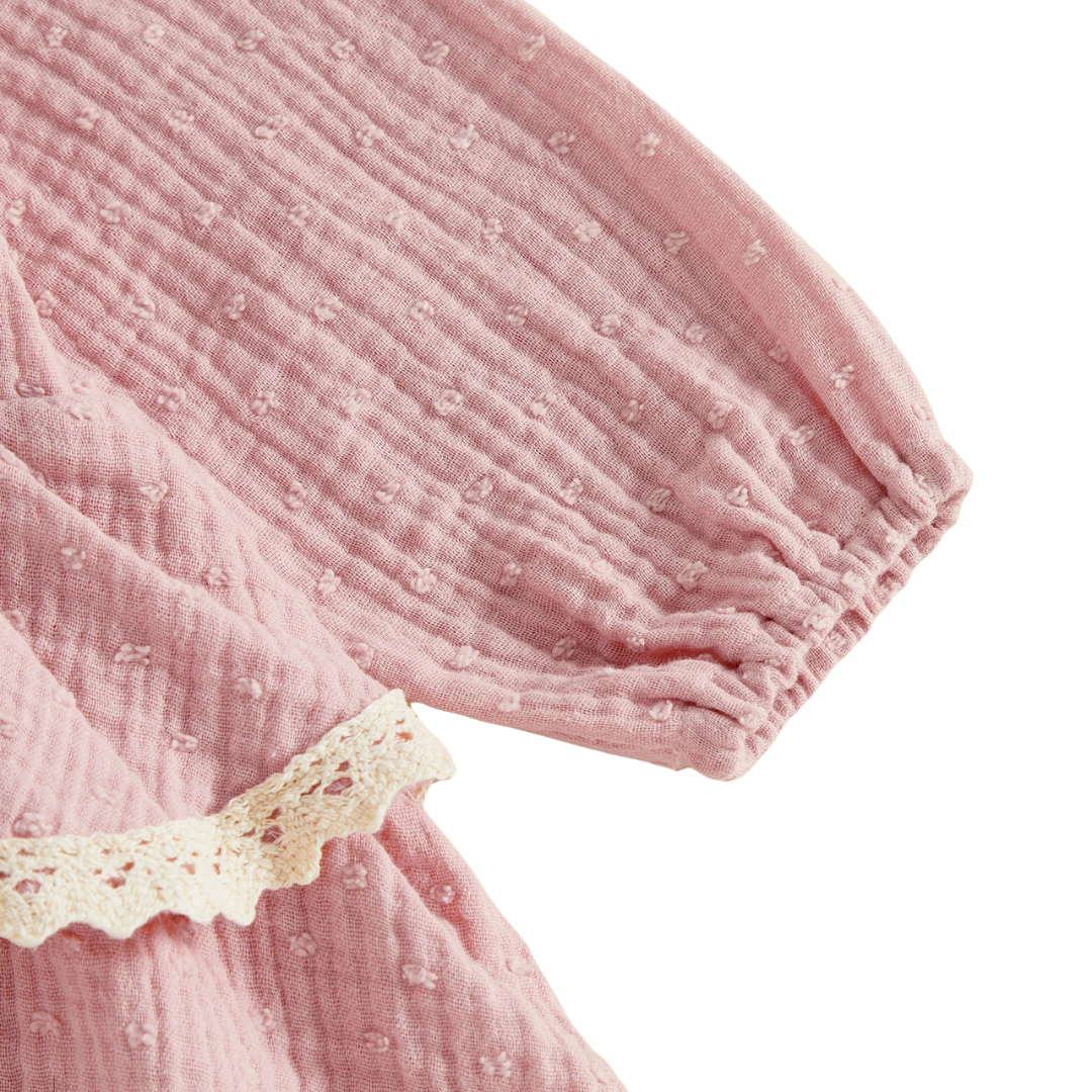 Close-up of the long puff sleeve, elastic cuff, and textured dotted muslin fabric on a pink baby girl romper.