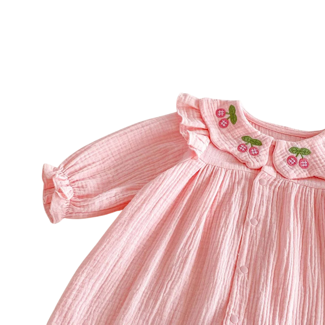 Close-up showing the shoulder seam, long sleeve, and collar detail of the pink baby girl jumpsuit.