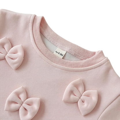 Close-up detail of the crew neckline and soft pink 3D bows securely attached to the toddler girl pullover sweatshirt.