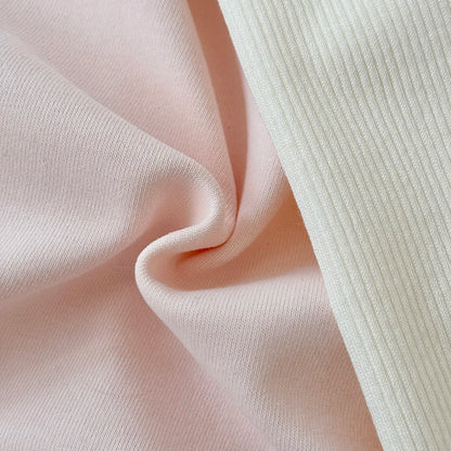 Close-up texture shot showing the smooth pink sweatshirt fabric next to the soft cream ribbed knit leggings fabric.