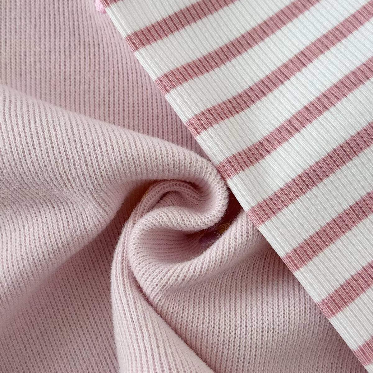 Close-up showing the soft textured fabric of the pink sweatshirt next to the ribbed pink and white striped leggings.