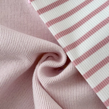 Close-up showing the soft textured fabric of the pink sweatshirt next to the ribbed pink and white striped leggings.