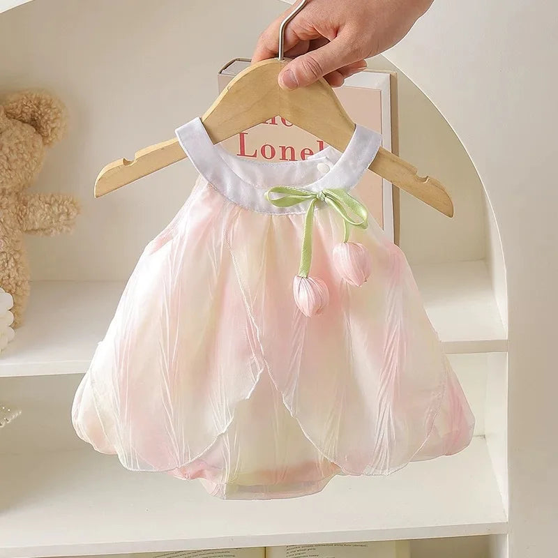 Front view of the pink and yellow tulip baby dress displayed on a wooden hanger.