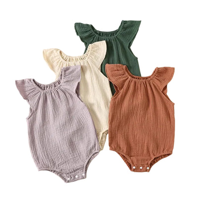 Four premium baby girl muslin rompers stacked together showing wild lavender, oatmeal milk, juniper pine, and terracotta colors.
