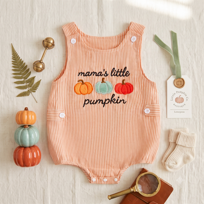 Flat lay of the orange striped mama's little pumpkin baby romper next to small decorative pumpkins and baby accessories.