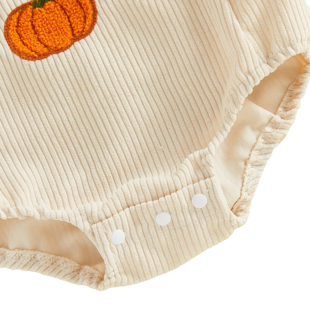 Close-up of the bottom snap closures for easy diaper changes on the beige baby corduroy bubble romper.