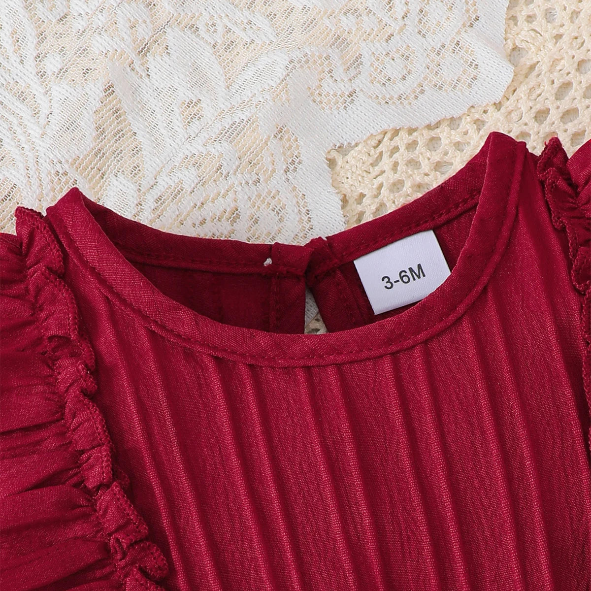 Close up of the back neckline on the dark red baby dress, showing the button closure and size tag.