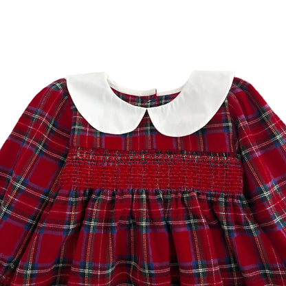 Close-up of white Peter Pan collar and intricate red smocking on baby girl Christmas outfit