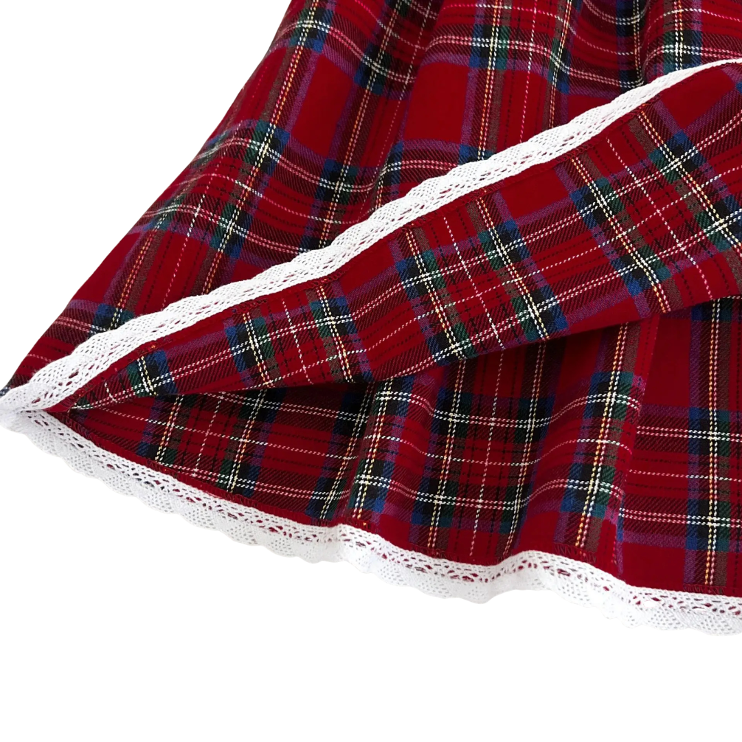 Close-up of fine lace trim detail along the bottom hem of red plaid Christmas dress