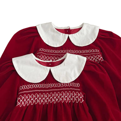 Close-up of the intricate chest smocking and crisp white Peter Pan collars on the matching red holiday outfits.