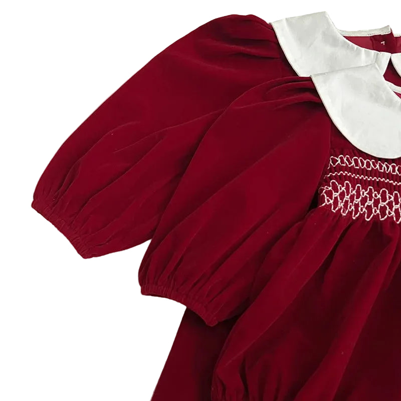 Close-up highlighting the long puff sleeves and rich red fabric of the smocked outfit.