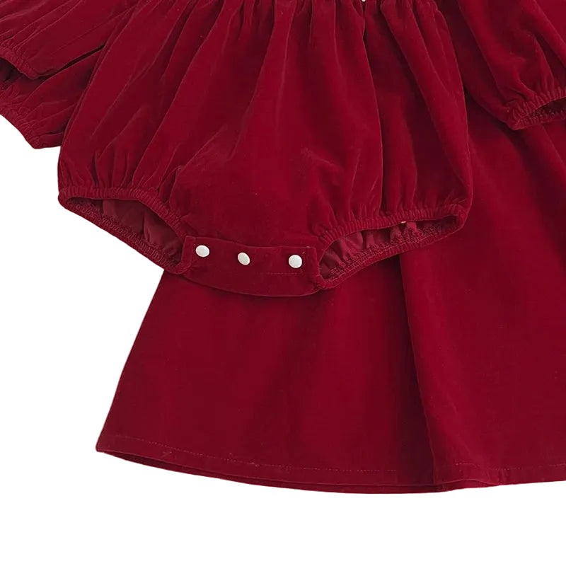 Close-up detail showing the convenient bottom snap closures on the baby girl's red bubble romper.