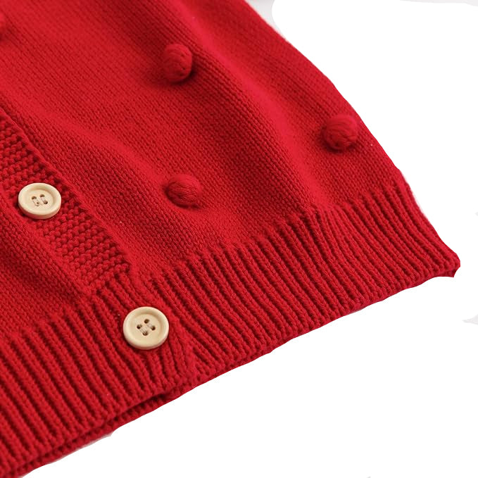 Close up of the red toddler sweater showing the ribbed bottom hem, wooden buttons, and pom-pom details.