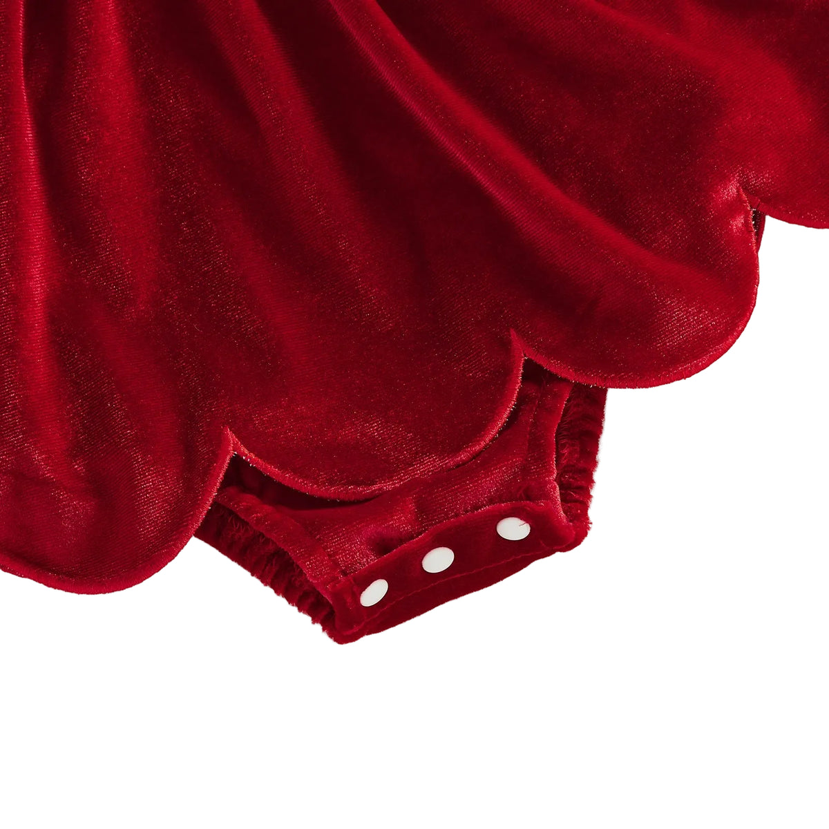 Detail view of the scalloped hem skirt and bottom snap closure on the baby velvet romper dress