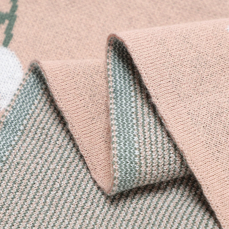 Close-up shot of the folded knit blanket showing the high-quality, reversible dual-sided jacquard weave of the tulip pattern.