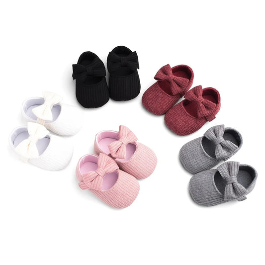 Collection of ribbed knit soft sole baby Mary Jane shoes in black, classic red, white, pink, and grey.