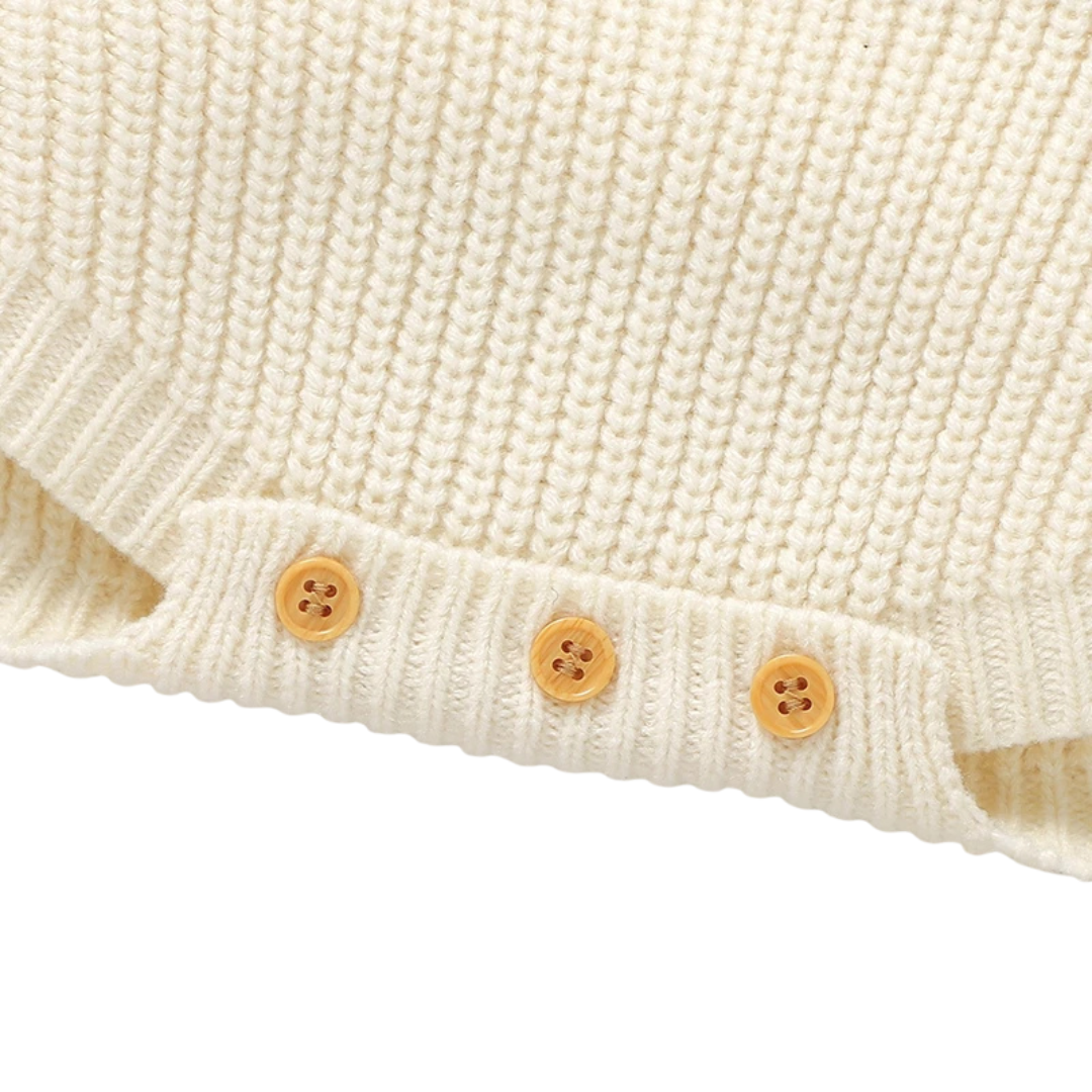 Close-up of the bottom crotch area of the cream knit romper, highlighting the three-button closure designed for easy diaper changes.