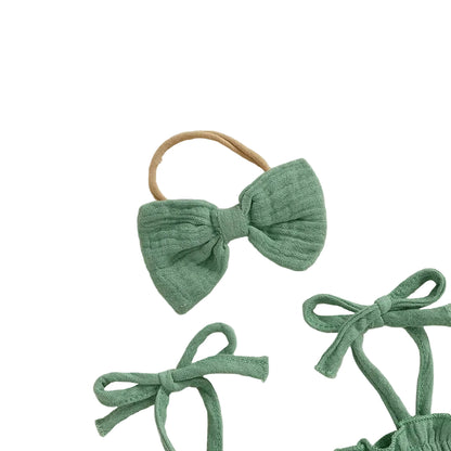 Detailed view of the matching green bow headband and the adjustable tie-shoulder straps of the birthday romper set.