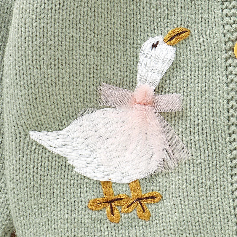 Close-up of the white embroidered goose with a 3D pink tulle bow on a sage green knit cardigan.