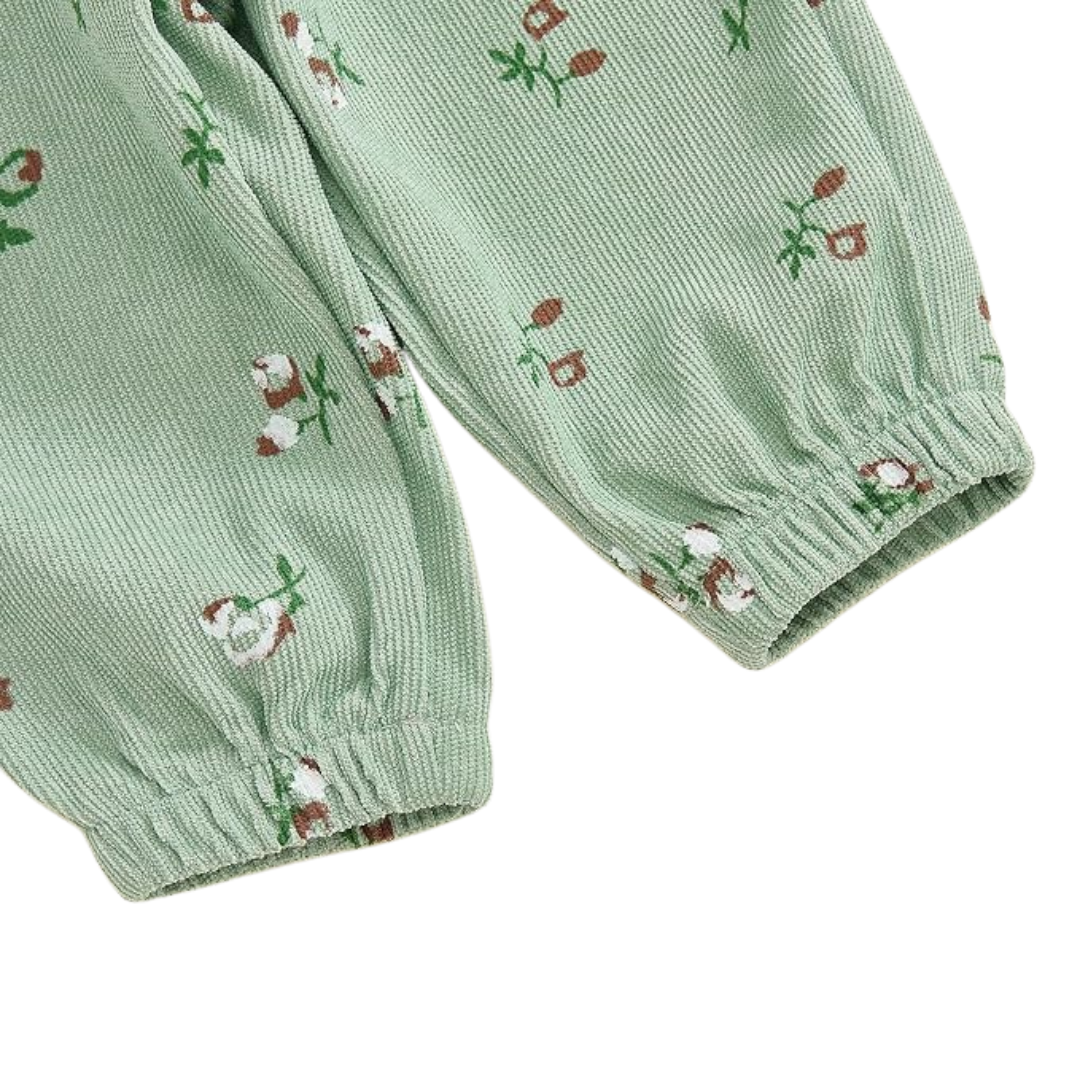 Close-up of sage green floral corduroy fabric on baby girl pants showing the ribbed texture, floral print, and elastic ankle cuffs.