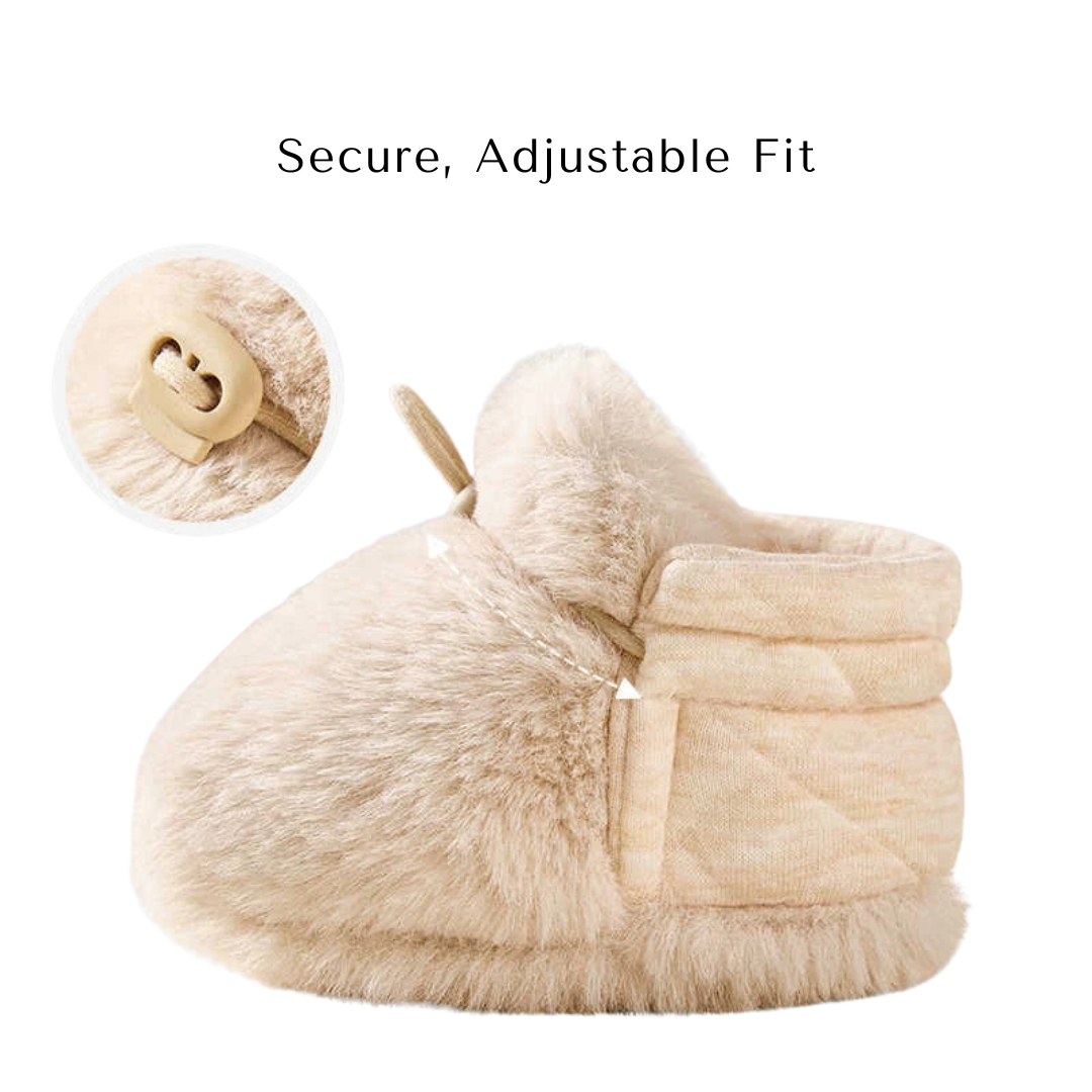 Side profile of a beige baby bootie highlighting the secure, adjustable fit toggle strap.
