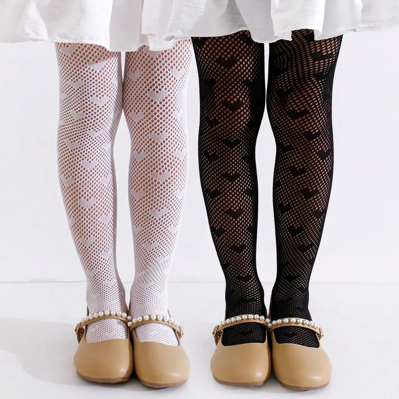two toddler girls standing side by side wearing white and black heart patterned tights