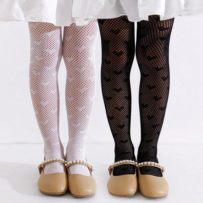 two toddler girls standing side by side wearing white and black heart patterned tights