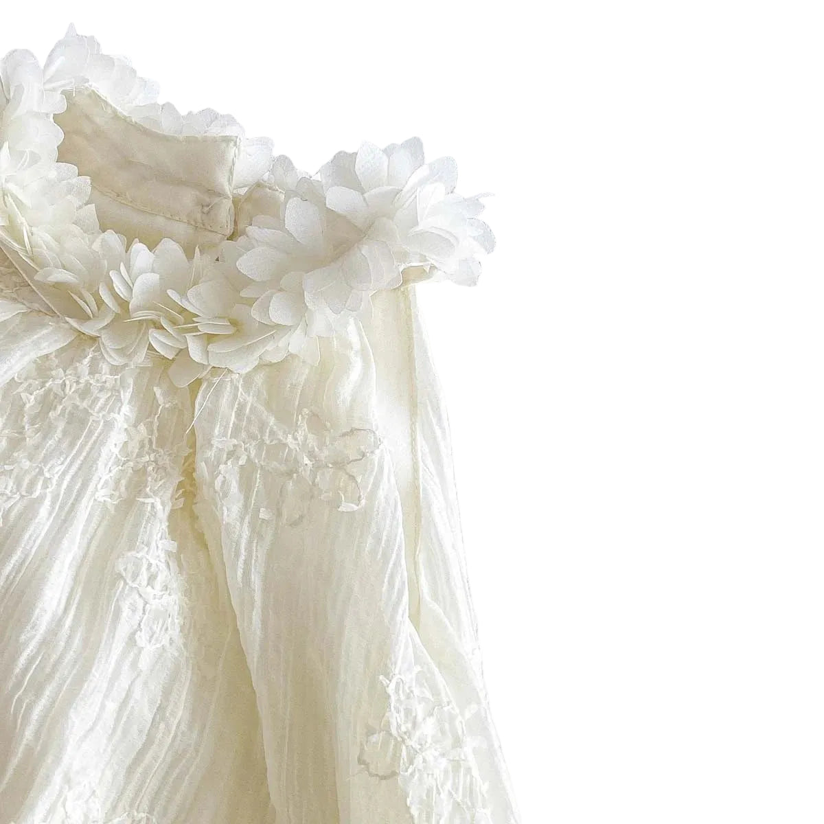Close-up showing the sleeveless armhole and textured fabric detail of the white baby girl bubble romper.