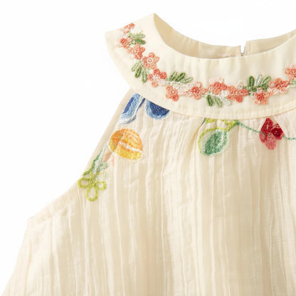Detail shot of the sleeveless halter-style armhole and upper floral embroidery on the ivory cotton-blend sundress.