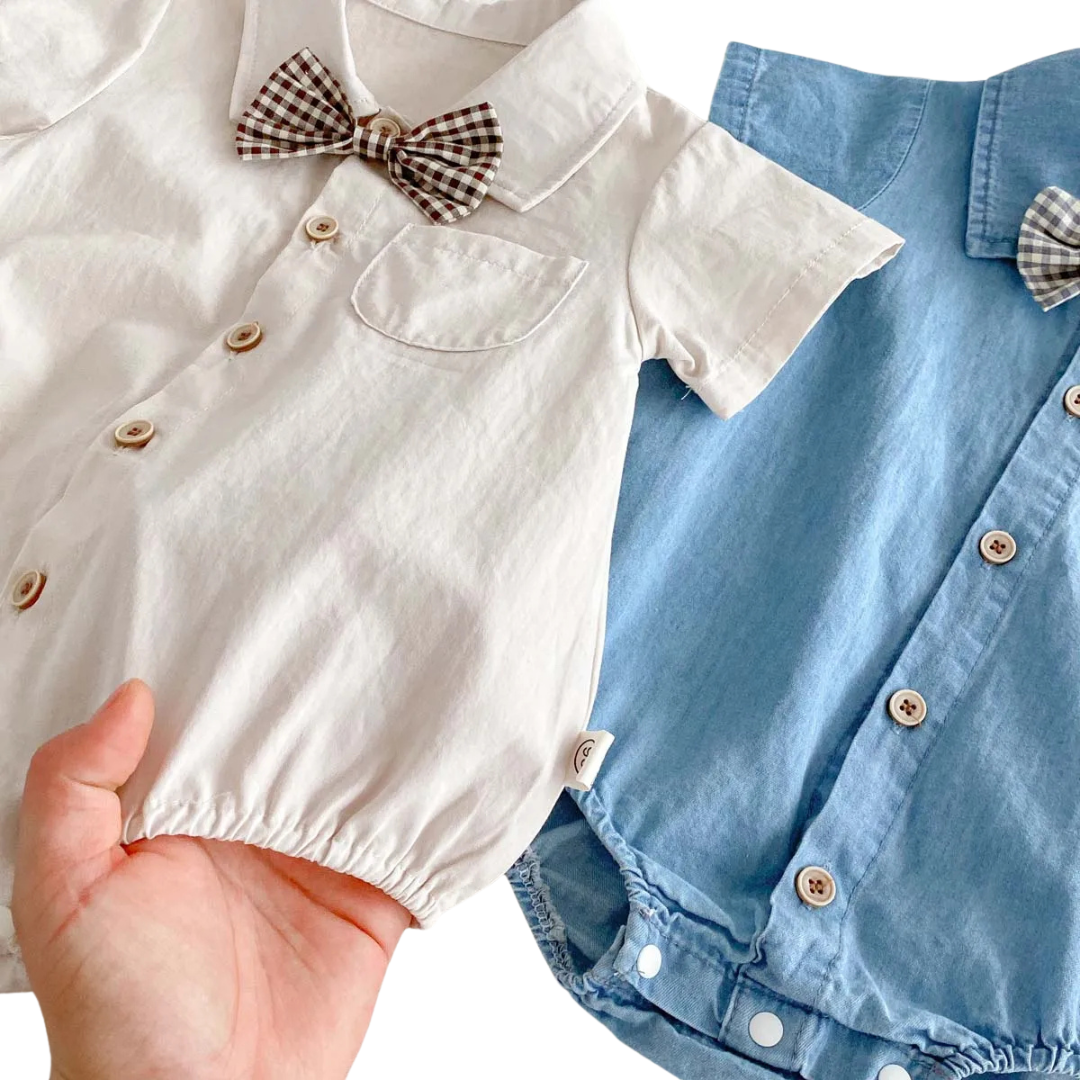 Close-up of a person holding the off-white cotton romper to show the soft fabric and elastic leg openings.