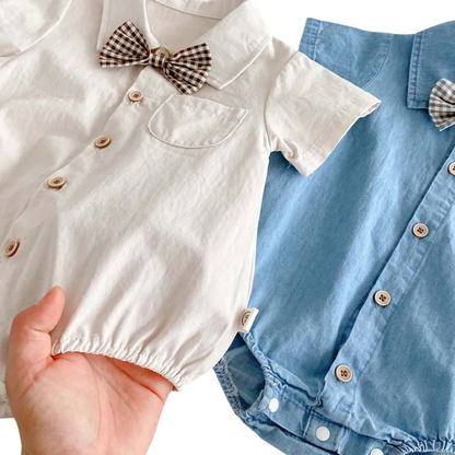 Close-up of a person holding the off-white cotton romper to show the soft fabric and elastic leg openings.